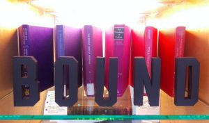 Crafted letters spelling " B O U N D" in front of multicolored books