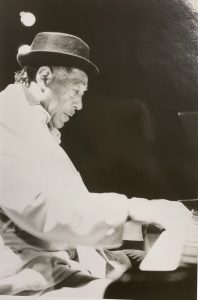 Black and white image of Duke Ellington sitting down, playing the piano. 
