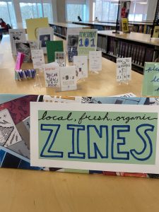 A display of student DIY publications behind a sign that reads "local, fresh, organic zines"