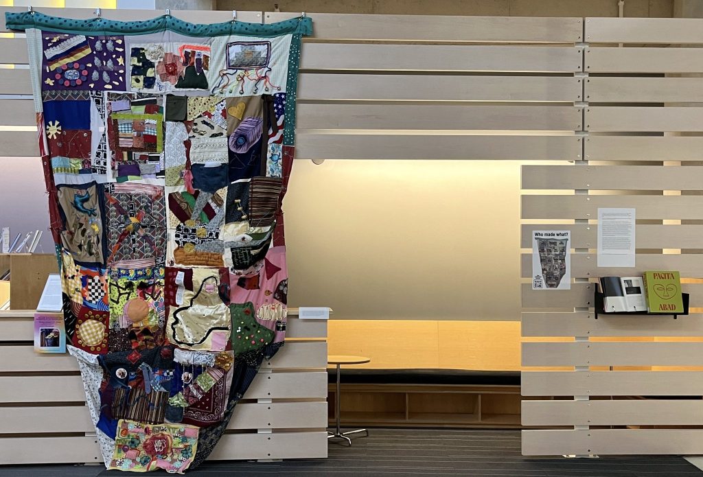 Photo of a trapunto quilt hanging on a wooden wall, with a written curatorial statement posted nearby.
